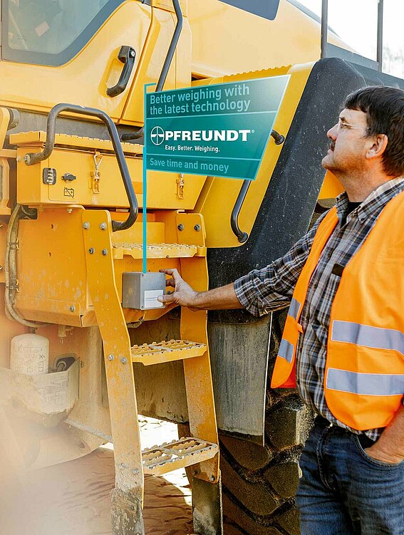 Man checks data on large, yellow construction site vehicle 